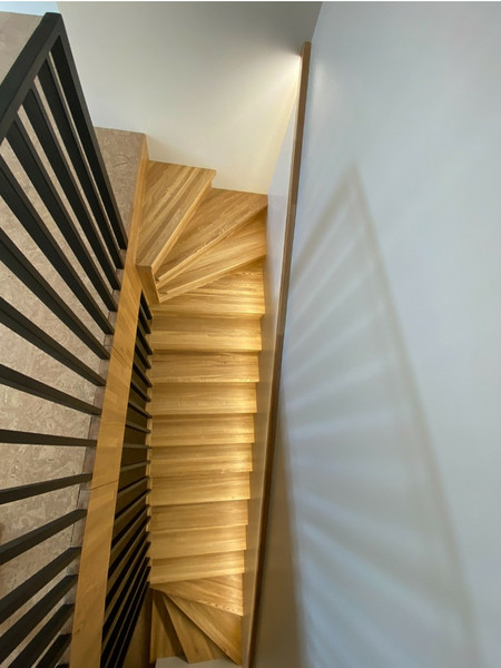 Лестница на металлическом каркасе закрытого типа с отделкой цельноламельными ступенями из ясеня и реечным ограждением в Дубне
