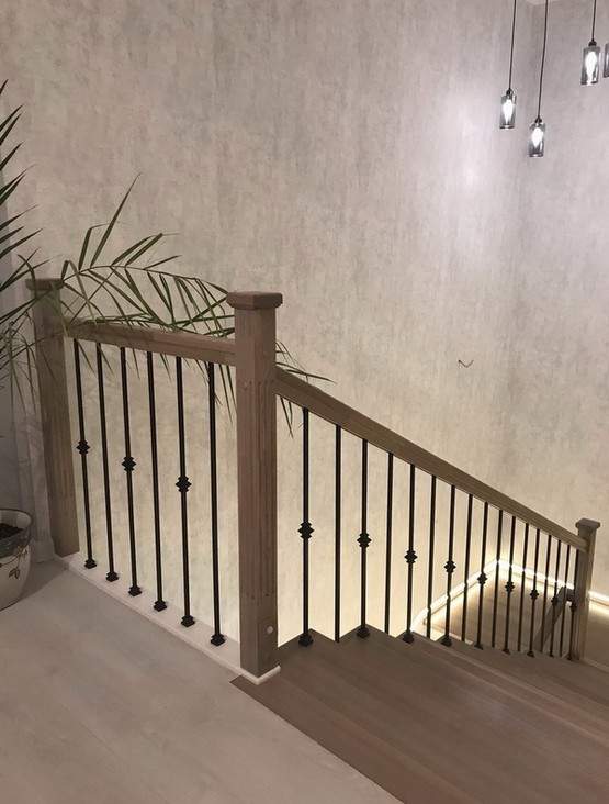 Отделка бетонной лестницы цельноламельными ступенями из ясеня и мдф с металлическими балясинами с горизонтальной подсветкой в Троицком
