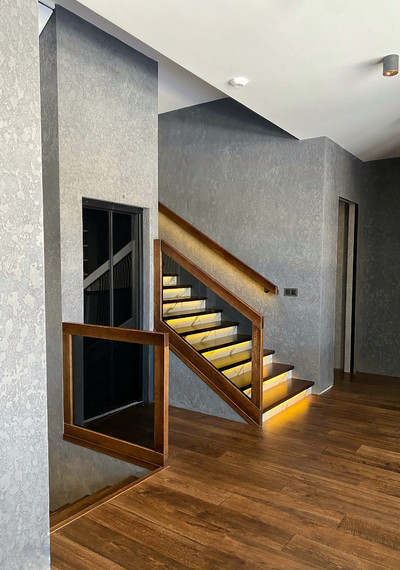 Лестница на закрытом металлическом каркасе вокруг лифта со стеклом и каменными подступенниками 5